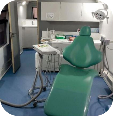 Modern mobile dental clinic interior featuring a green dentist chair, medical equipment, and white cabinetry for mobile oral healthcare